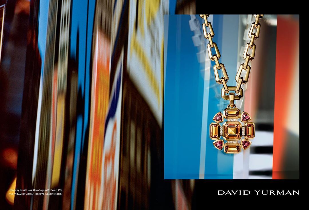 Elegant gold chain necklace with gemstone pendant showcased against abstract urban background, emphasizing luxury and modern design.