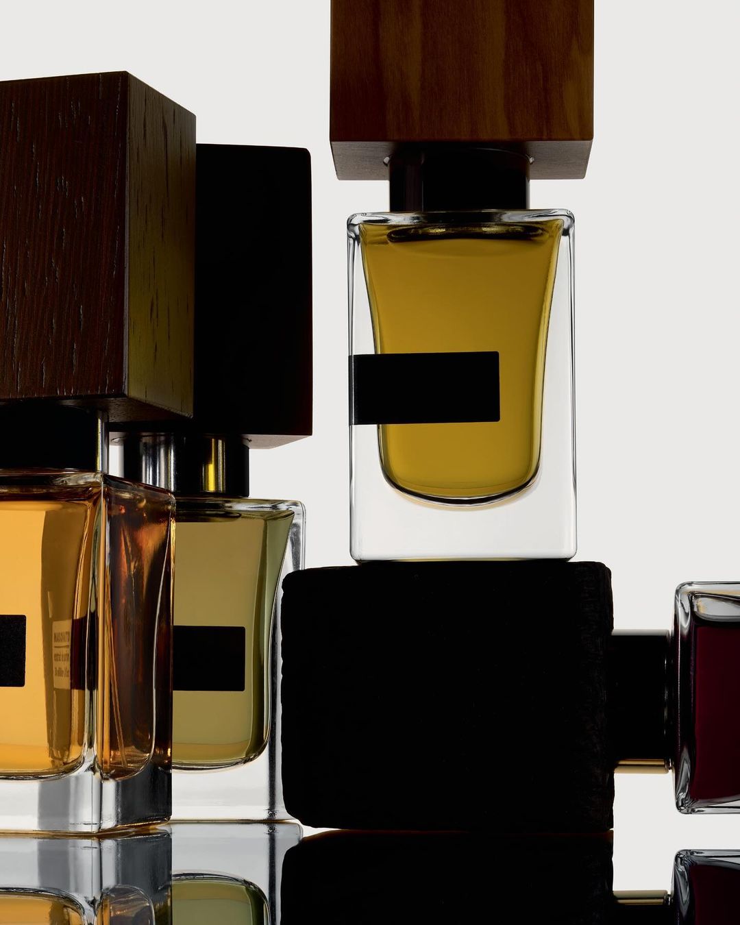 Several perfume bottles with clear glass and dark brown wooden caps arranged in a minimalistic, eye-level product shot on a white surface.