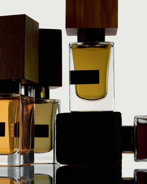 Several perfume bottles with clear glass and dark brown wooden caps arranged in a minimalistic, eye-level product shot on a white surface.
