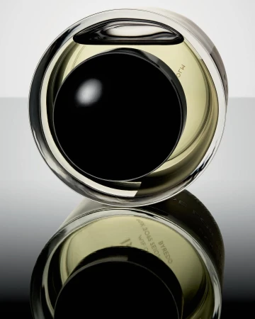 Close-up shot of a reflective, rounded Byredo perfume bottle with a black cap, showcasing its unique design against a gradient backdrop.