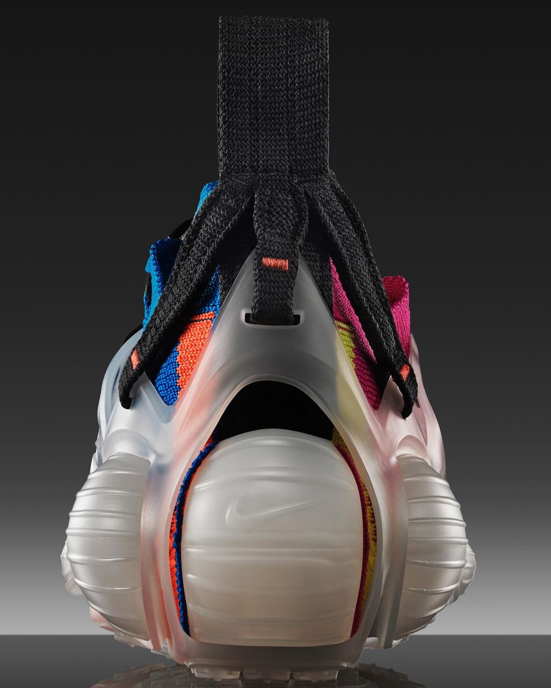 Close-up of colorful Nike running shoe with clear heel support. The shoe has a black fabric loop on the back. The background is dark.