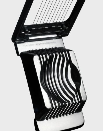 Close-up shot of a black and silver egg slicer, featuring a hinged design with wires for slicing, set against a neutral background.