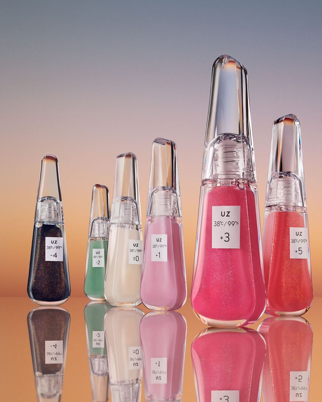 Six transparent cosmetic bottles with different colored liquids and white labels standing on a reflective surface against a gradient background.