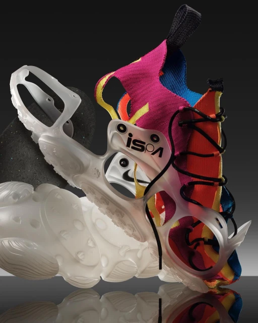 A close-up studio shot of a deconstructed Nike ISPA shoe showcasing its unique design, materials, and construction details against a gray background.