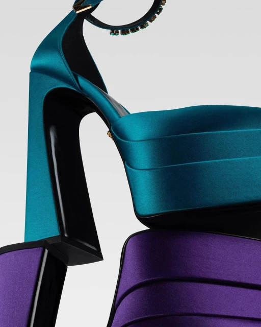 Close-up shot of a platform high heel shoe in teal and purple satin material, featuring a chunky block heel, on a neutral background.