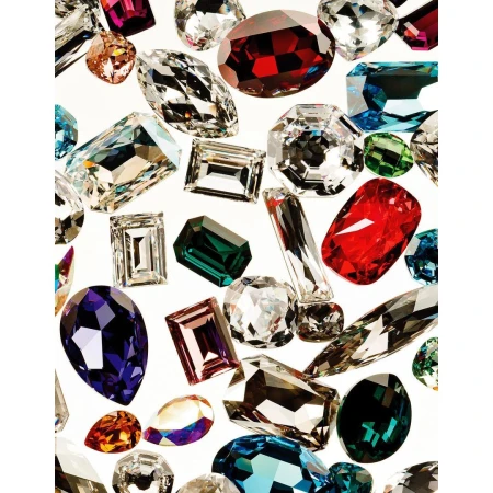 Various shaped gems of different colors against a white background, faceted to catch the light, arranged close together in a random pattern.