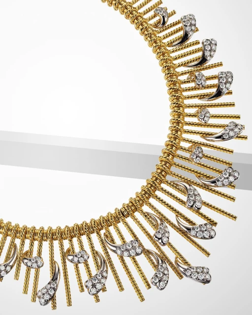 Close-up of a gold necklace featuring diamond accents on a white surface, highlighting jewelry's craftsmanship and sparkle.