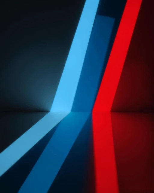 Abstract image featuring blue and red light bars diagonally aligned against a dark gray background with reflections visible on a smooth surface.
