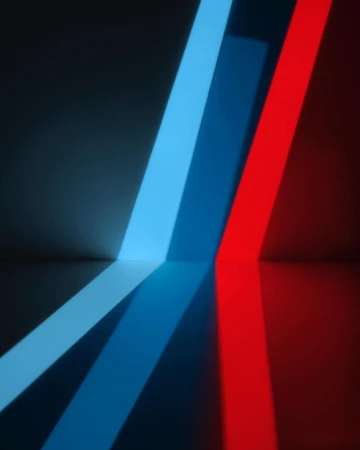 Abstract image featuring blue and red light bars diagonally aligned against a dark gray background with reflections visible on a smooth surface.