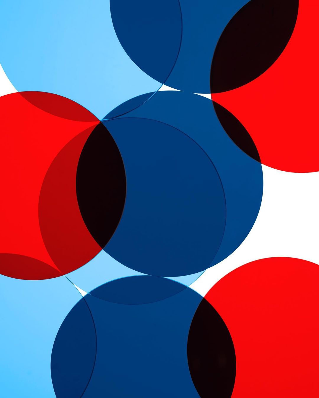 Overlapping geometric shapes, including semi-transparent red, blue, and light blue circles, create a vibrant abstract design on white.