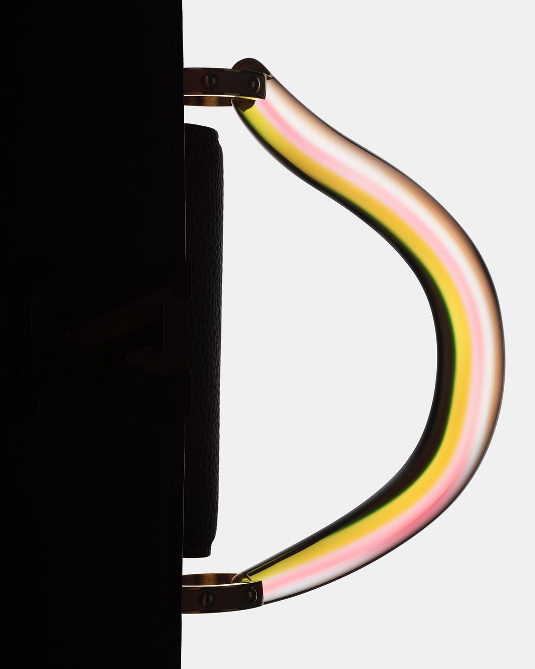 Black handbag with a colorful striped, transparent handle against a light grey backdrop, showing a sleek and modern design.