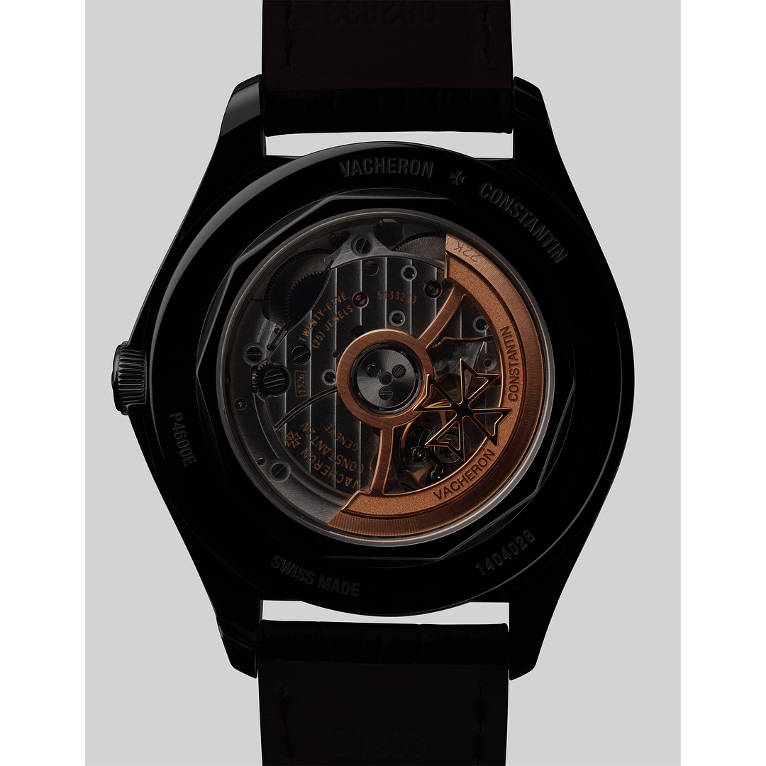 Close-up of a Vacheron Constantin watch, showcasing its intricate inner mechanism and a black strap against a neutral backdrop.