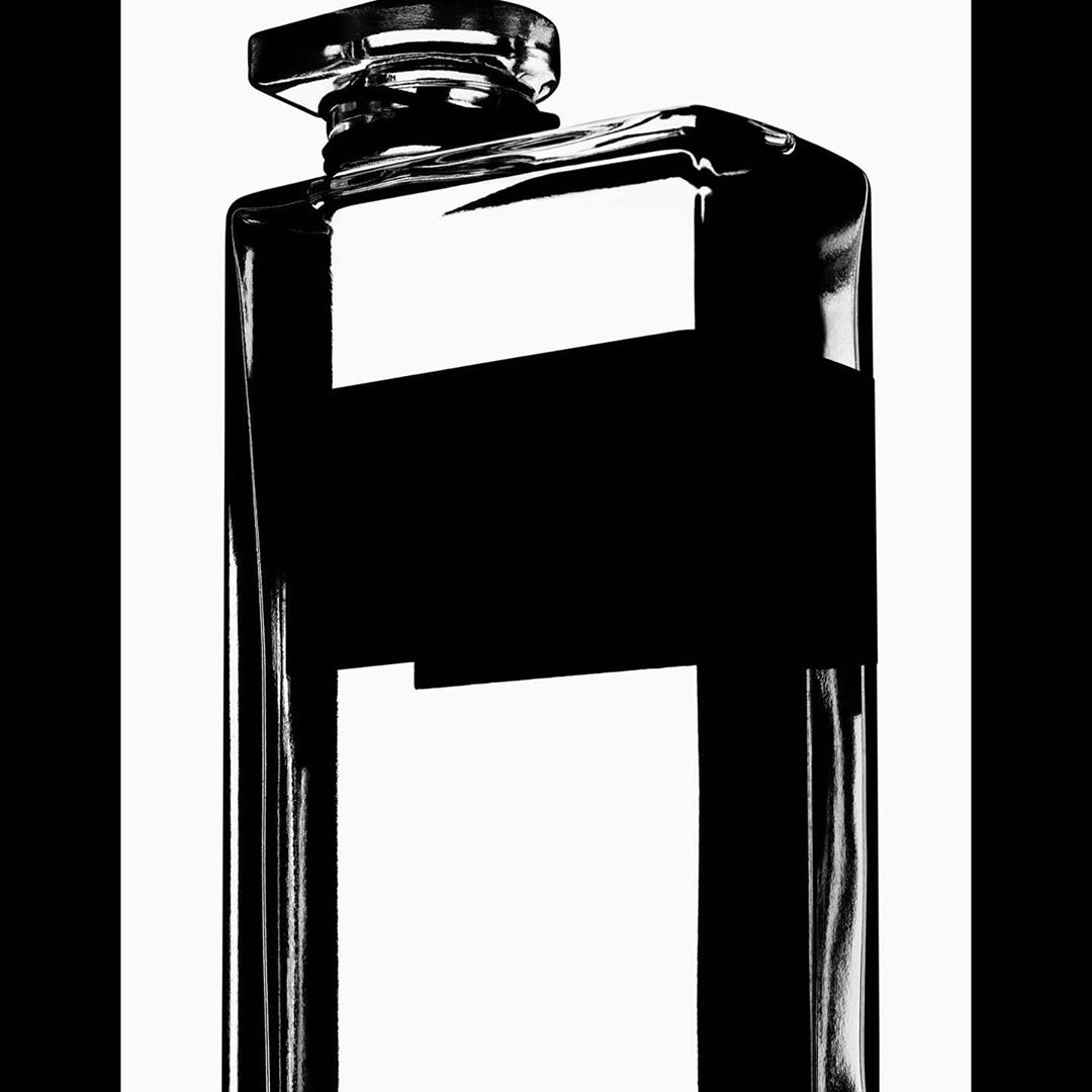 High-contrast black and white studio photograph of a rectangular glass perfume bottle by Robin Broadbent