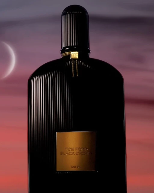 Elegant studio shot of Tom Ford Black Orchid perfume bottle against a dreamy purple and orange sky with a crescent moon.