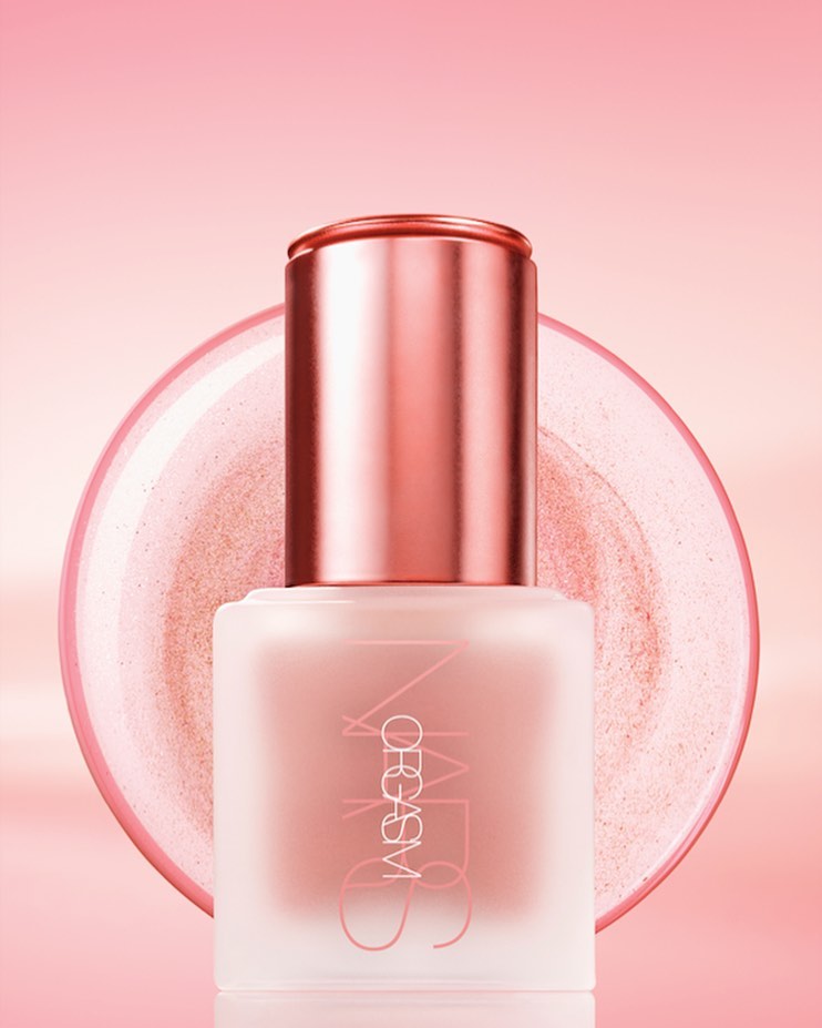 Close-up studio shot of a pink bottle of NARS Orgasm liquid blush with reflective accents and a matching pink background gradient.