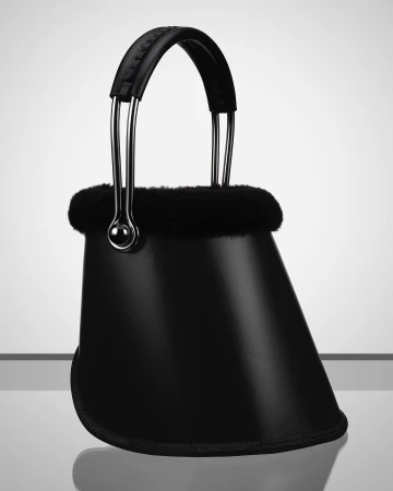 Studio shot of a black designer handbag with metal accents and a fur trim, set against a gradated grey and white background for fashion.