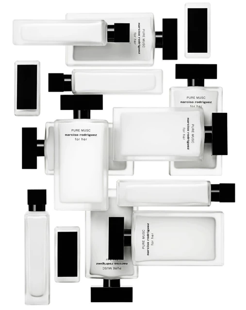 Multiple rectangular, white glass perfume bottles with black caps arranged at various angles on a white background. Close-up of fragrance products.