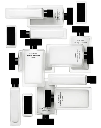 Multiple rectangular, white glass perfume bottles with black caps arranged at various angles on a white background. Close-up of fragrance products.