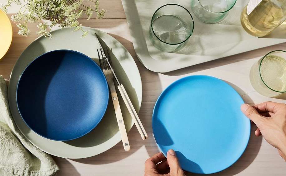 Overhead shot of table setting with plates, cutlery, glassware, and linen, emphasizing modern tableware and minimalist styling.