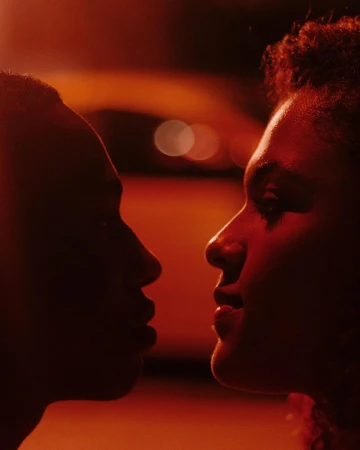 Close-up profile portraits of two people facing each other under dramatic red lighting in Paris