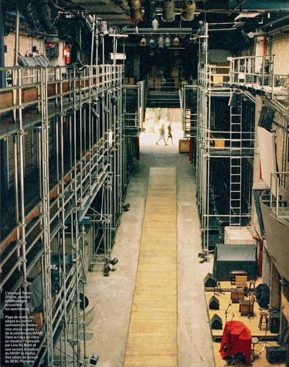 An interior shot of a performance or music venue. Scaffolding lines the sides of the large hall with stage lighting equipment overhead.