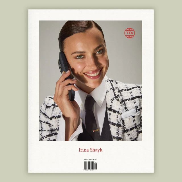 Smiling brunette woman with professional styling in a white and black jacket on a phone in a close up studio shot.