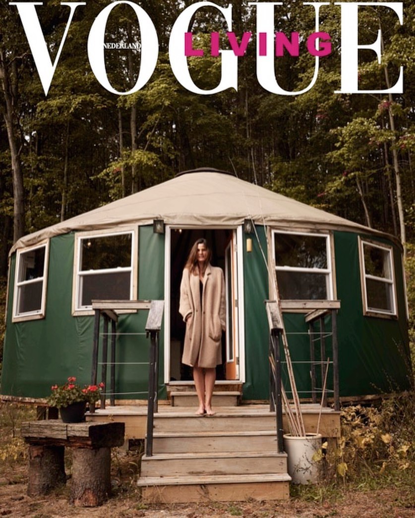 Vogue Nederland cover featuring a woman standing on the steps of a green yurt in a forest setting, fashion, nature, architecture.