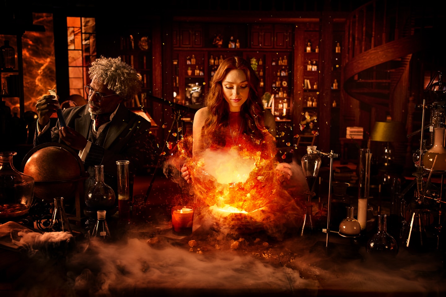 Two people, one male and one female, in a dimly lit room with shelves of bottles and a table with beakers and flasks. The woman is surrounded by an orange glow.