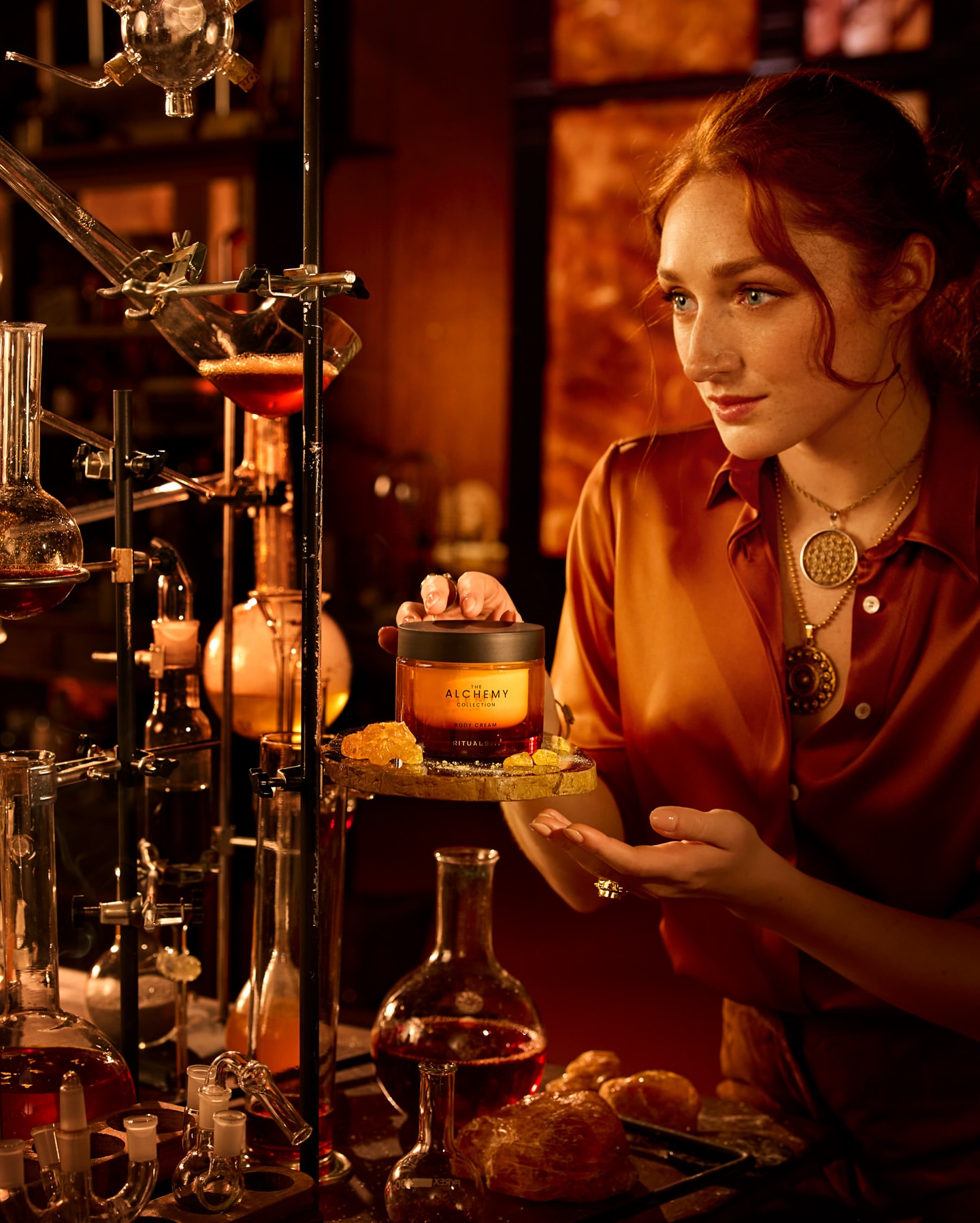 Young woman holding a jar of skincare product in a warm, dimly lit setting with glass beakers and various laboratory objects.