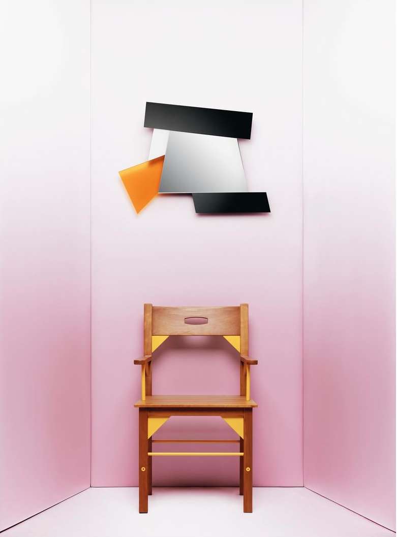 Minimalist interior set featuring a wooden chair with yellow accents placed beneath a modern abstract mirror against a pink wall backdrop.