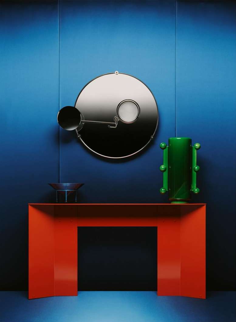 Modern interior design with a red console table, decorative mirror, and green vase against a gradient blue wall.
