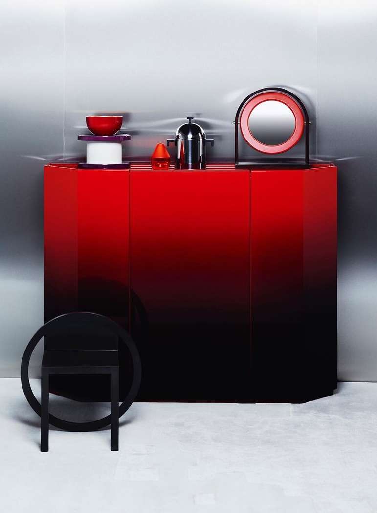Elegant modern interior featuring a red-to-black gradient cabinet with a minimalist black chair, decorative bowls, and a round mirror.