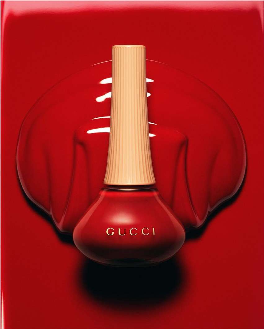 Close-up studio shot of a Gucci nail polish bottle on a red surface, creating a glossy, high-fashion beauty product image.