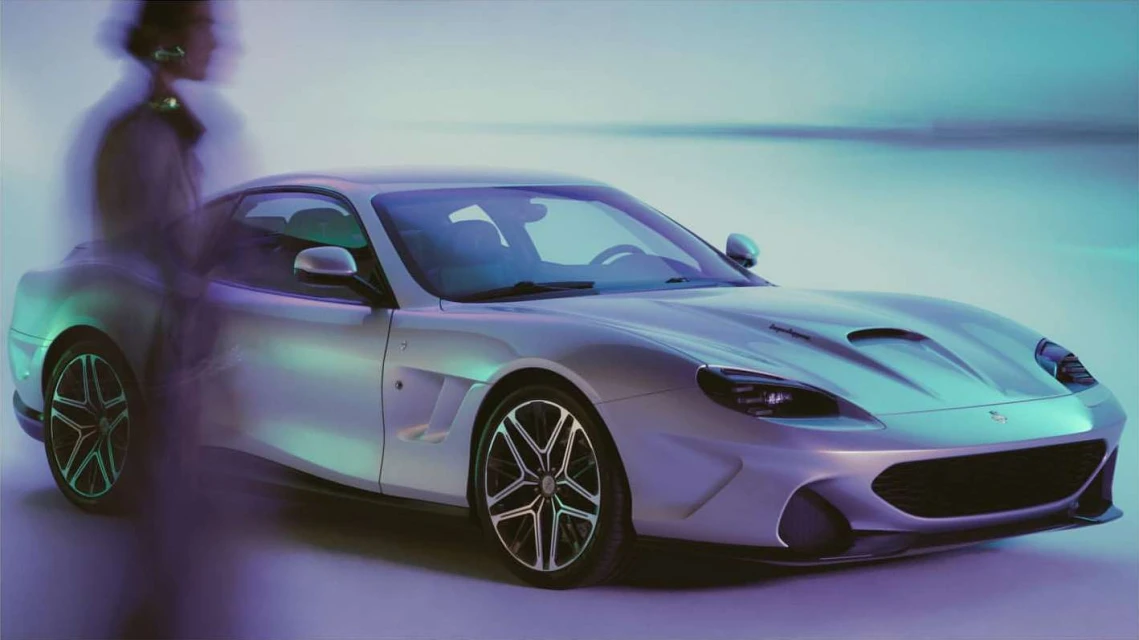 Sleek silver sports car showcased in studio lighting, with a blurred human figure subtly positioned in the background for context.