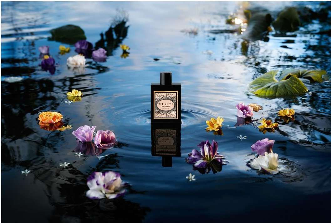 Gucci Bloom Profumo di Fiori perfume bottle surrounded by flowers floating on water, product shot for beauty and fashion industry.