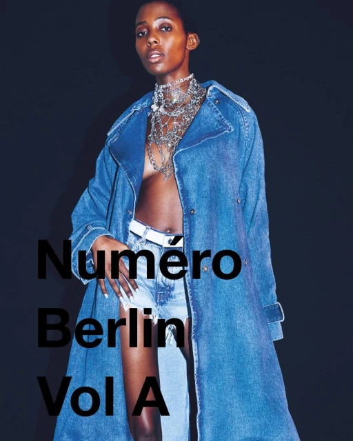 Fashion editorial shot of a Black woman wearing a denim coat and jewelry, posing against a dark background with magazine text overlay.