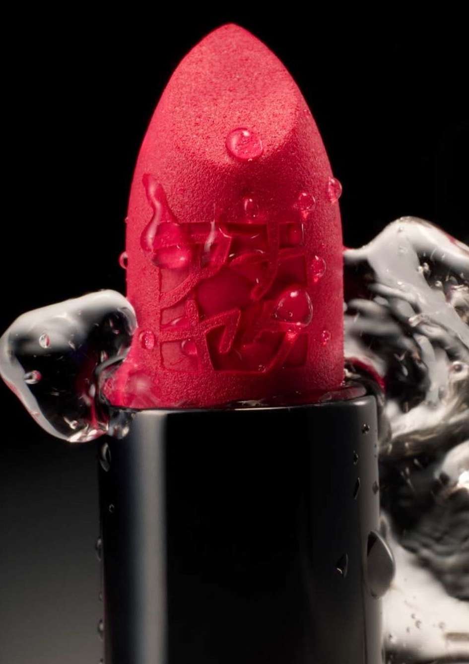 Close-up of a red lipstick with water droplets on black background. Cosmetic product photography of beauty and make-up item.