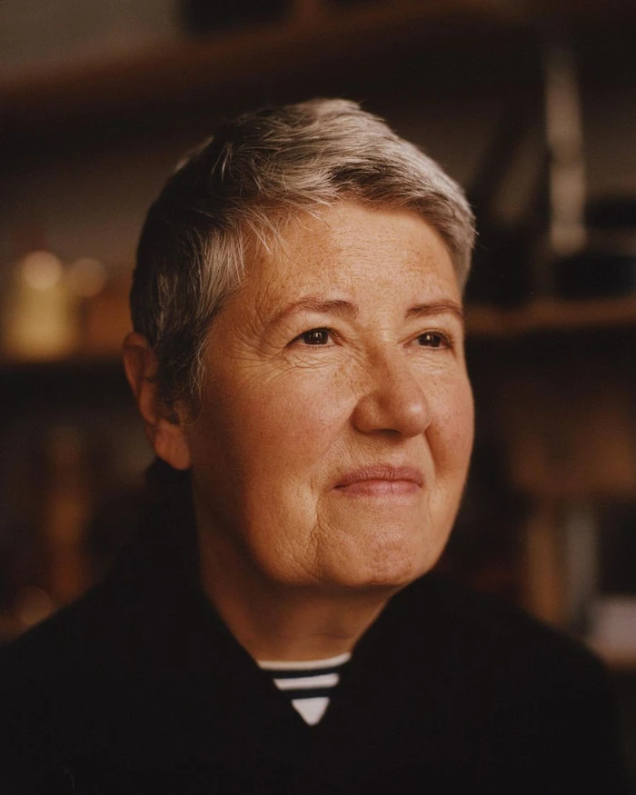 Portrait of an elderly woman with short grey hair and a serene expression wearing a dark collared shirt.