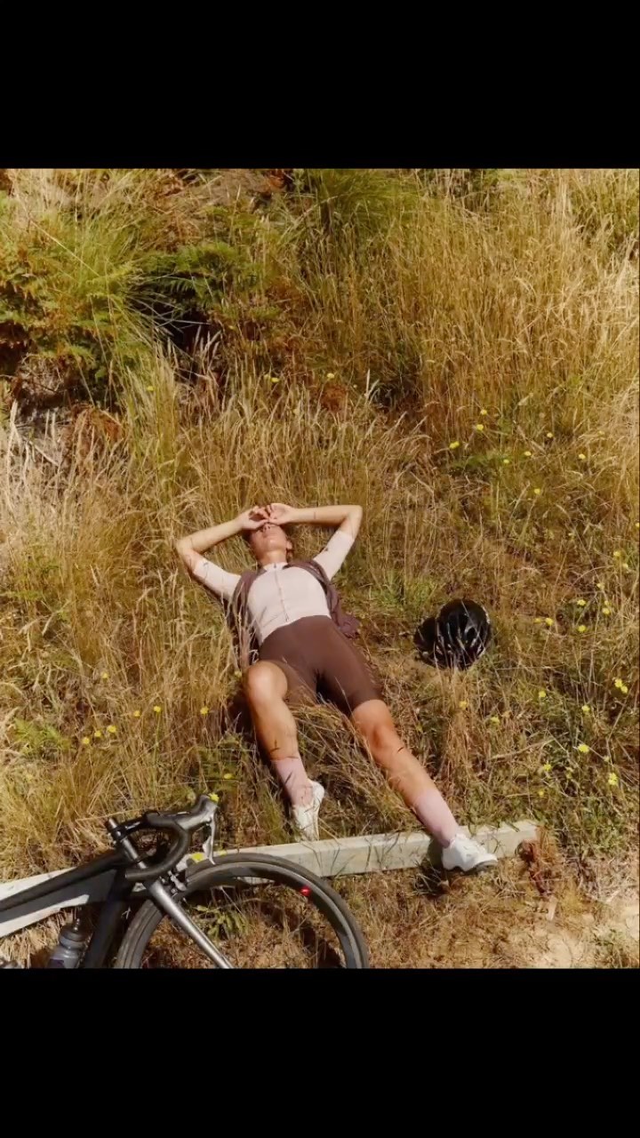 Adult cyclist lying in golden field with bicycle and helmet after a ride. Relaxing in nature.