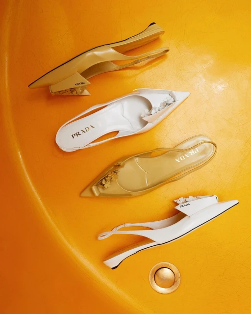 Four fashionable Prada slingback shoes in varying cream, white, and translucent colors arranged in a spiral pattern on a yellow background.