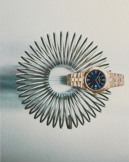 A rose gold luxury wristwatch on a stainless steel spring on a light grey background, showcasing elegance, precision, and craftsmanship.