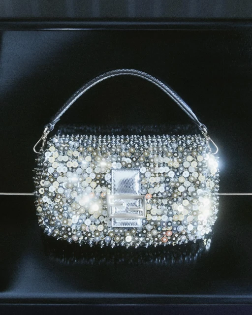 Fendi Baguette handbag with a silver handle and embellished with silver sequins and pearl beads against a dark glossy background.