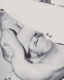 Black and white portrait of a person with short hair intertwined in a close embrace, captured by Rosie Harriet Ellis.