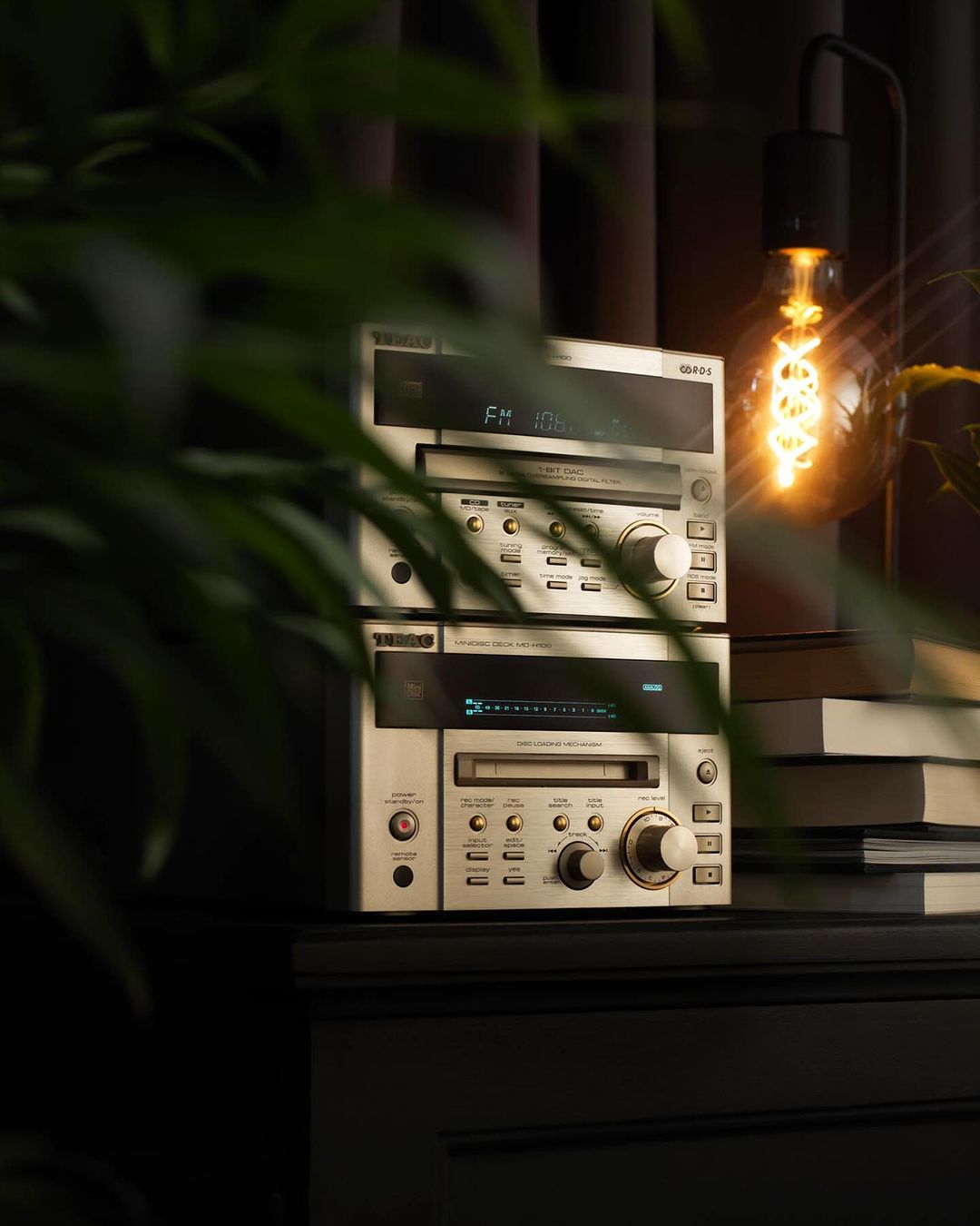 Close-up of a vintage stereo system with a lamp in a dim interior, showing retro audio equipment with an illuminated bulb and plant.