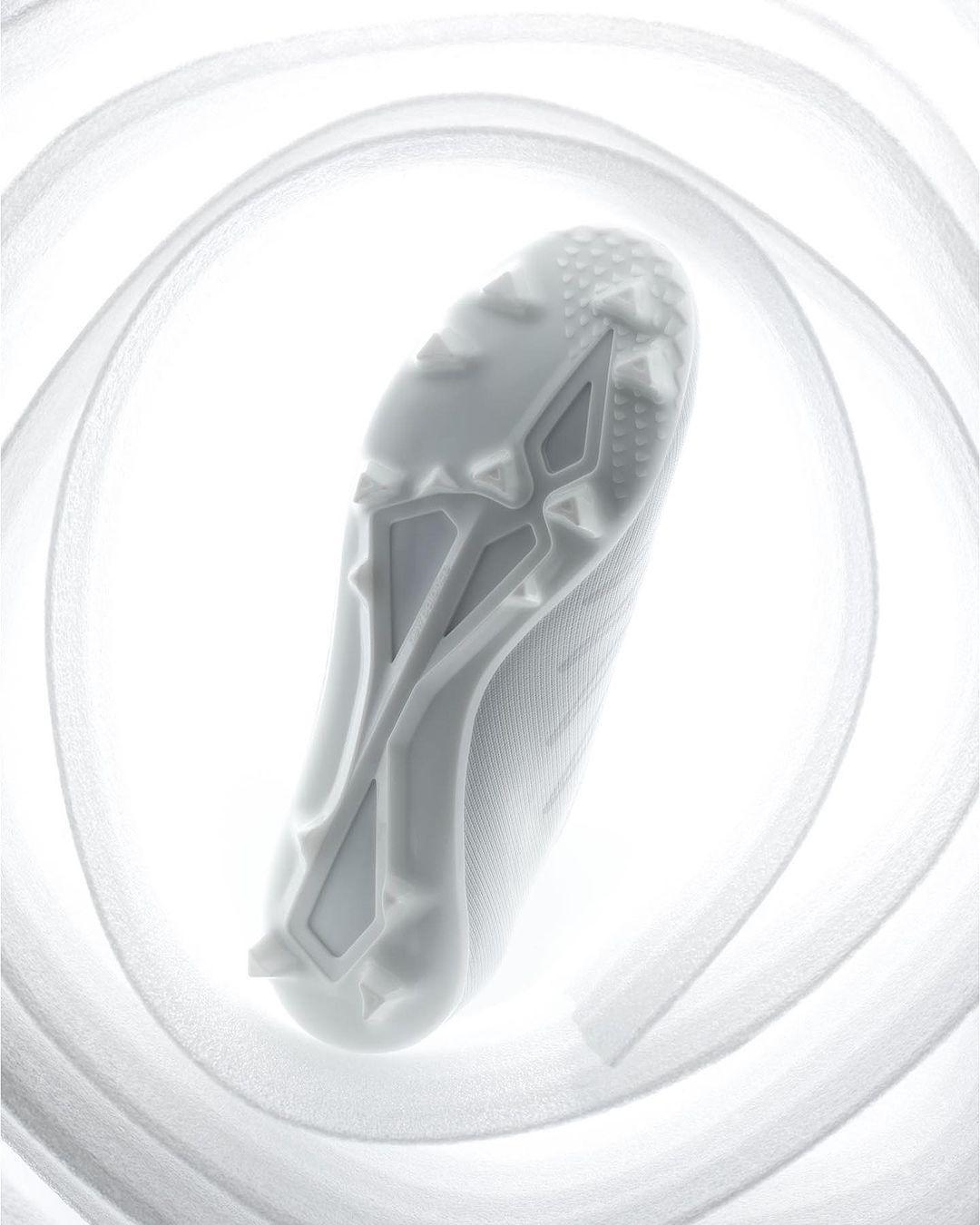A close-up, high-angle shot captures the sole of a white athletic shoe surrounded by a spiraling white ribbon on a bright background.