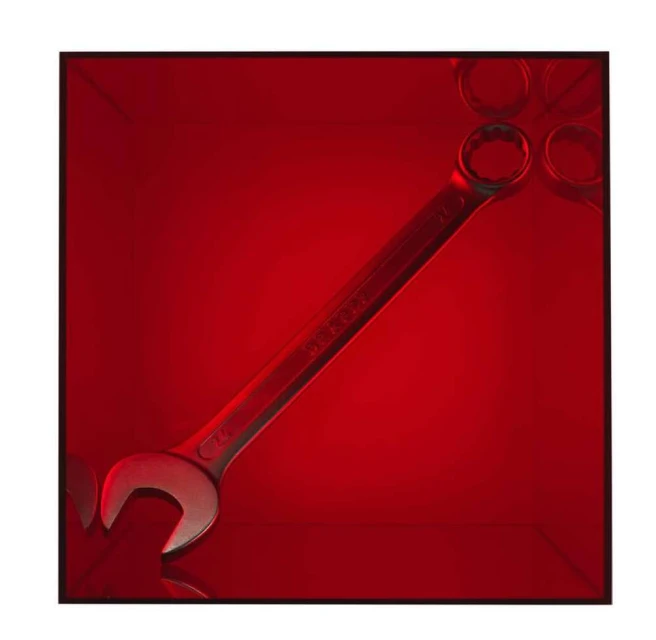 Close-up studio shot of a silver-tone combination wrench with box end and open end against a graduated red backdrop with tool outlines.
