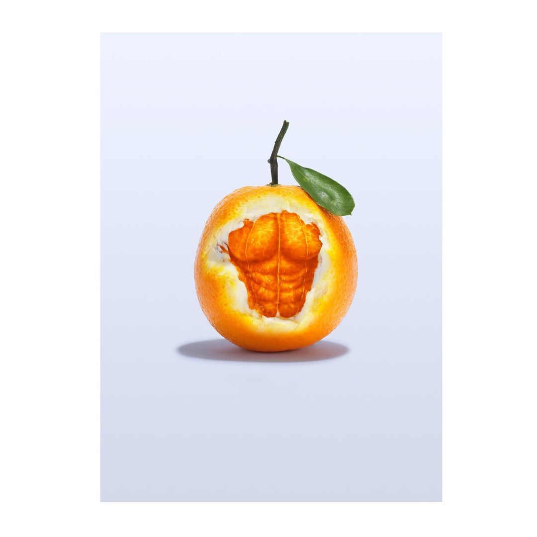 Still life of an orange fruit with an imprint of abdominal muscles, isolated against a light-blue background in a studio shot.