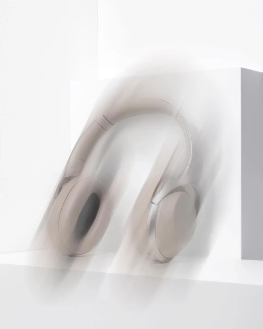 Studio shot of beige wireless headphones against a white background with motion blur effect emphasizing movement and sleek design.