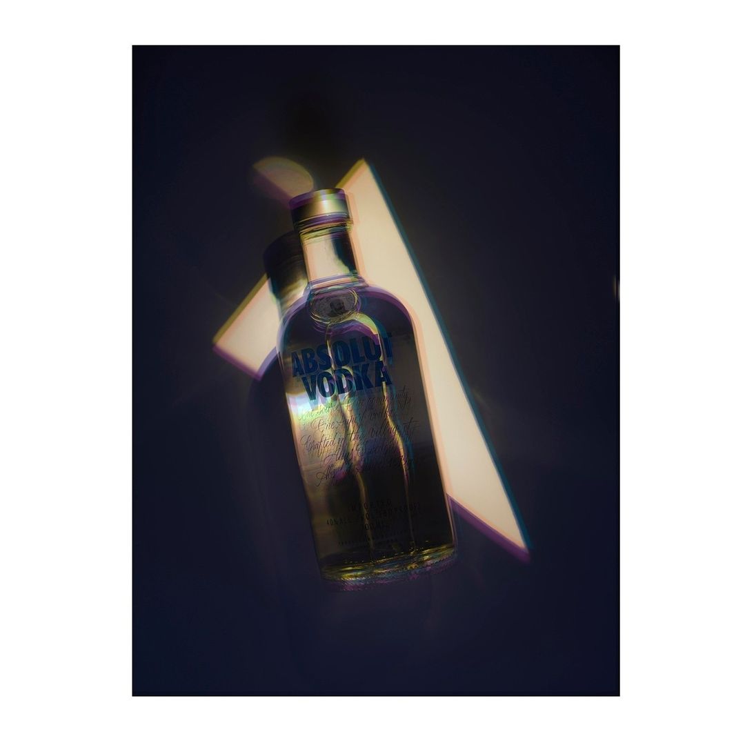 Absolut Vodka bottle photographed indoors with professional lighting, showcasing the clear bottle and geometric shapes on a dark backdrop.