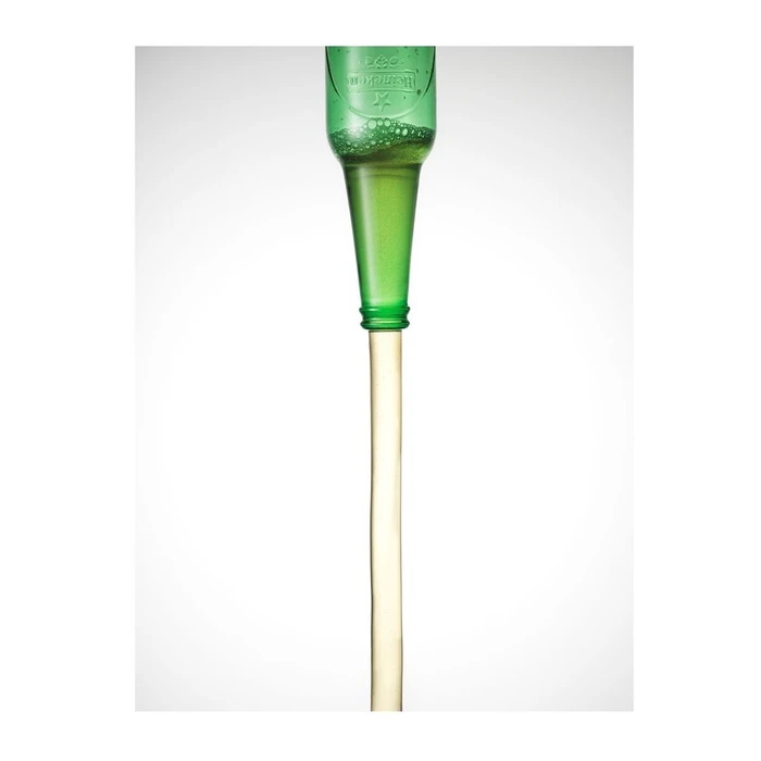 Green glass beer bottle upside down pouring liquid against a white seamless background